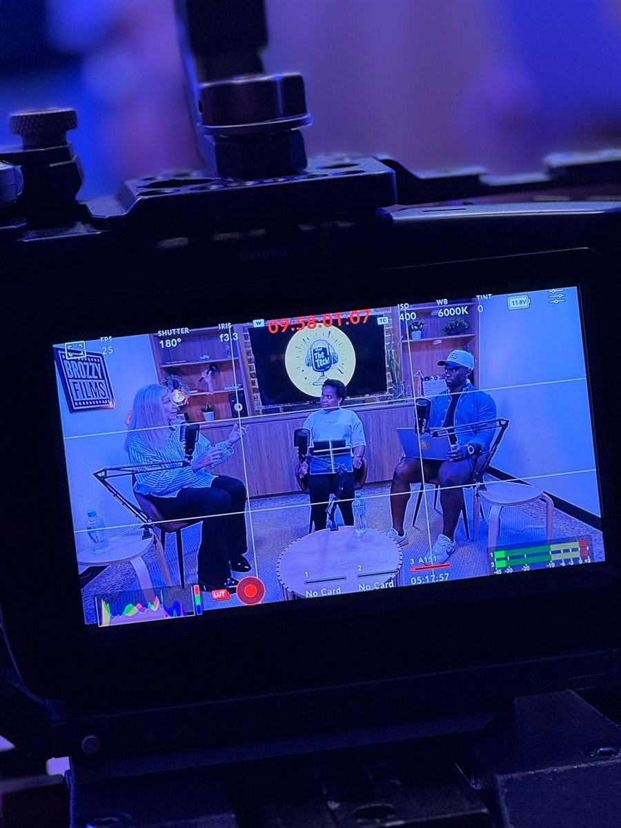 A Blackmagic monitor showing the framed three-shot of a podcast recording in progress